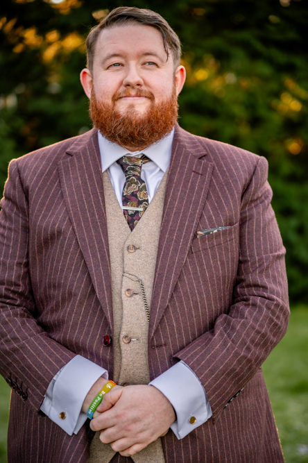 Groom brown suit with sun shining through trees behind