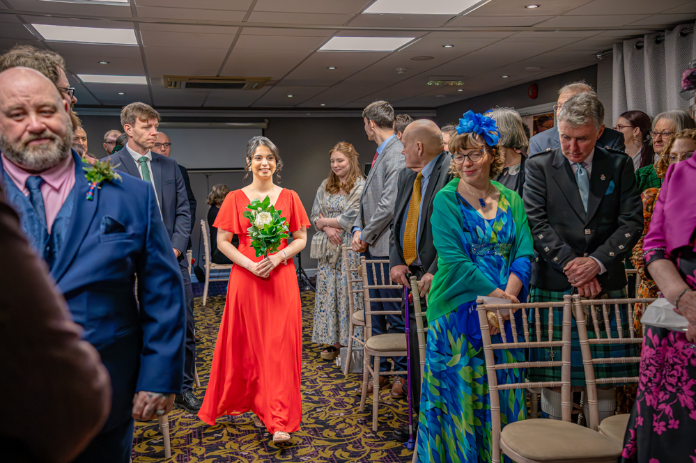 Bridesmaid walking down the isle in a red dress