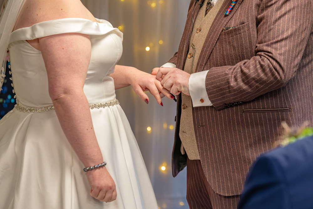 groom putting the ring on brides hand.