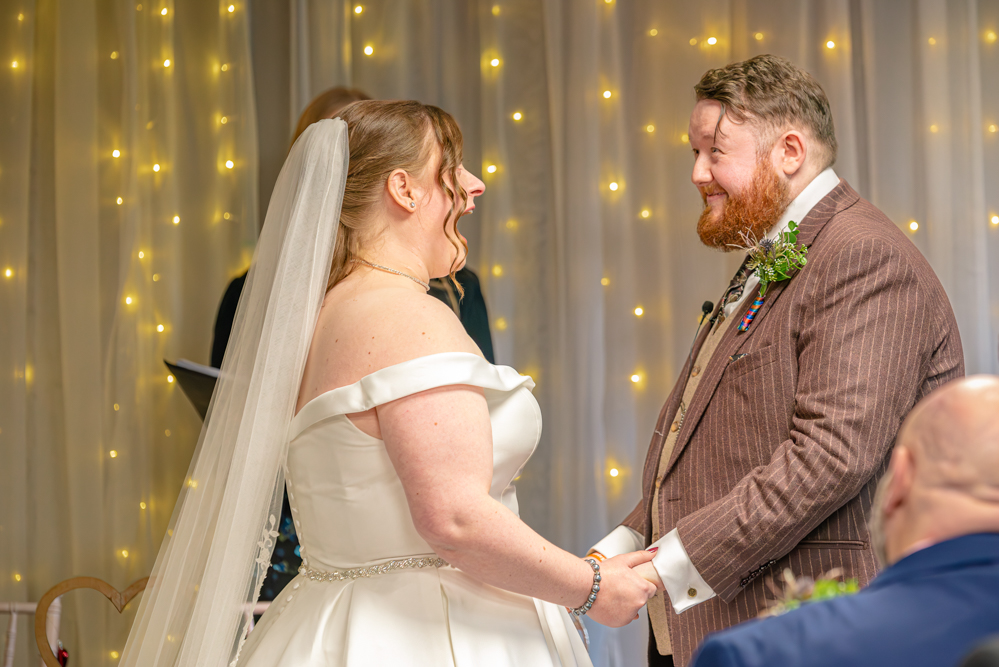 bride and groom holding hands at the front of the ceremony, smiling and laughing