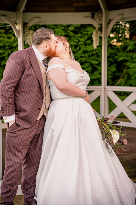 bride and groom kissing with bandstand behind them taken by Manchester Photographer Wedding Rebekah Morecroft