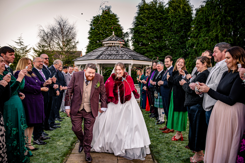 Bride and Groom with wedding guests lined up popping poppers over them