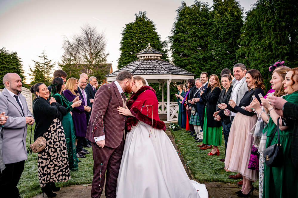 Bride and groom kissing as confetti is thrown during their wedding celebration
