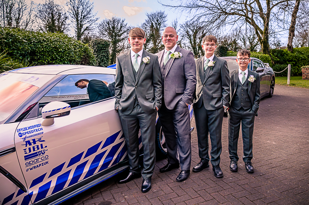 Groom with his groomsmen standing next to a grey with blue strips Nissan GT-R