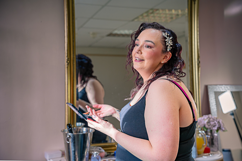Bride smiling while doing her makeup.