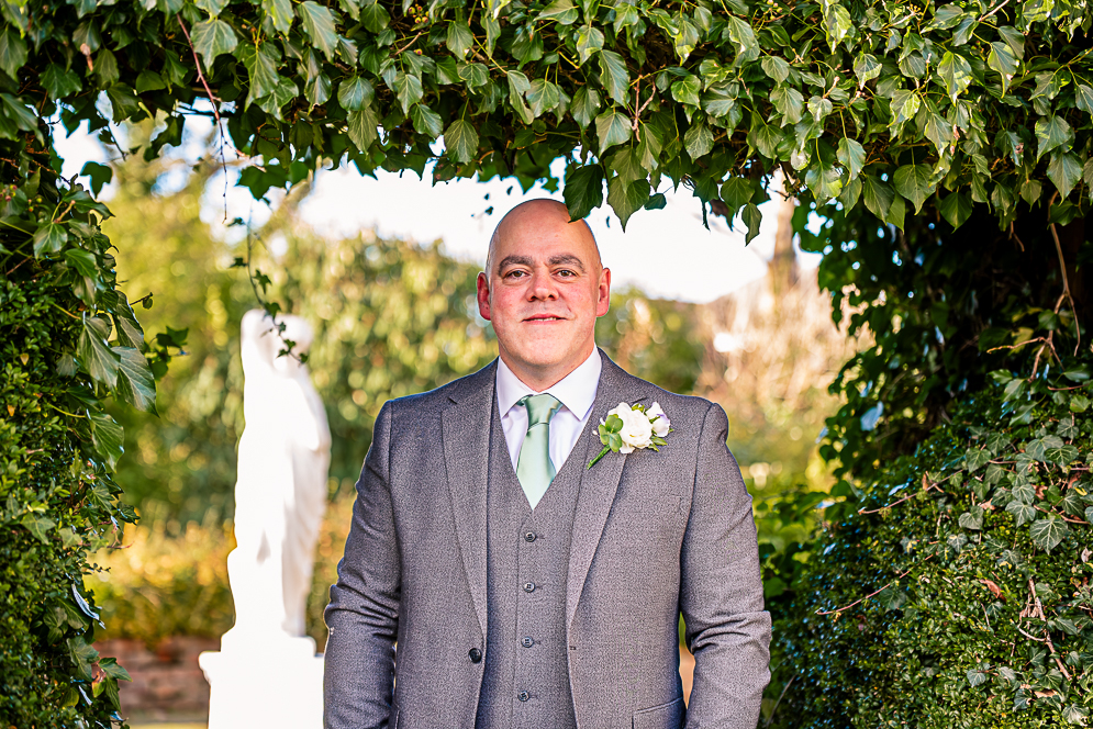 Groom under a leaf shaped arch taken by Manchester Photographer Wedding Rebekah Morecroft