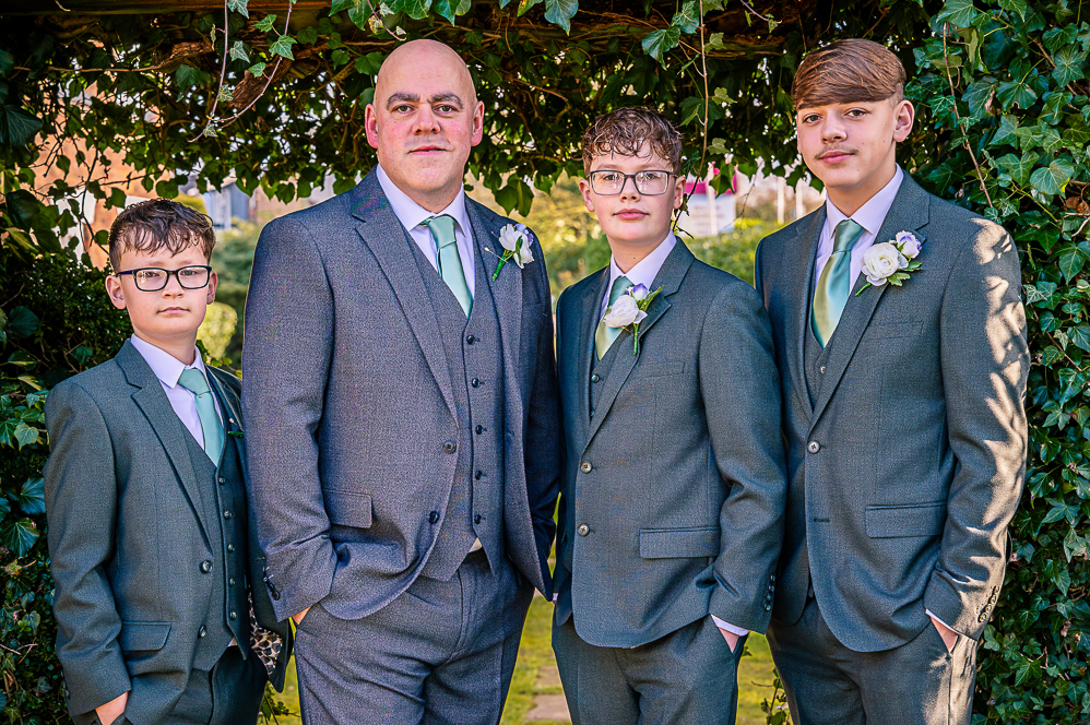 Groom and 3 groomsmen (boys) under a leaf shaped arch taken by Manchester Photographer Wedding Rebekah Morecroft