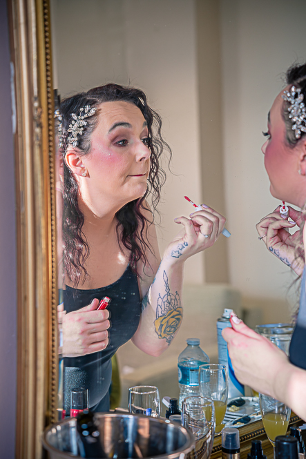 Bride looking at herself in the mirror while doing her makeup.