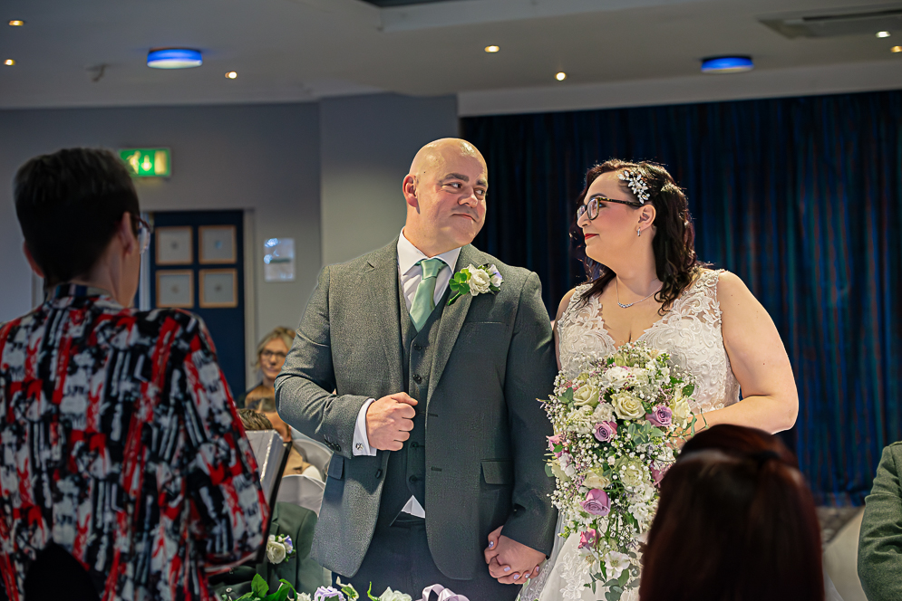 Bride and Groom looking at each other at the top of the aisle during their wedding ceremony at Bolton Georgian House Hotel By Rebekah, a Bolton and Manchester Wedding Photographer