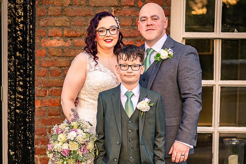 Bride and Groom with Groomsman (boy) standing in front of Georgian style building