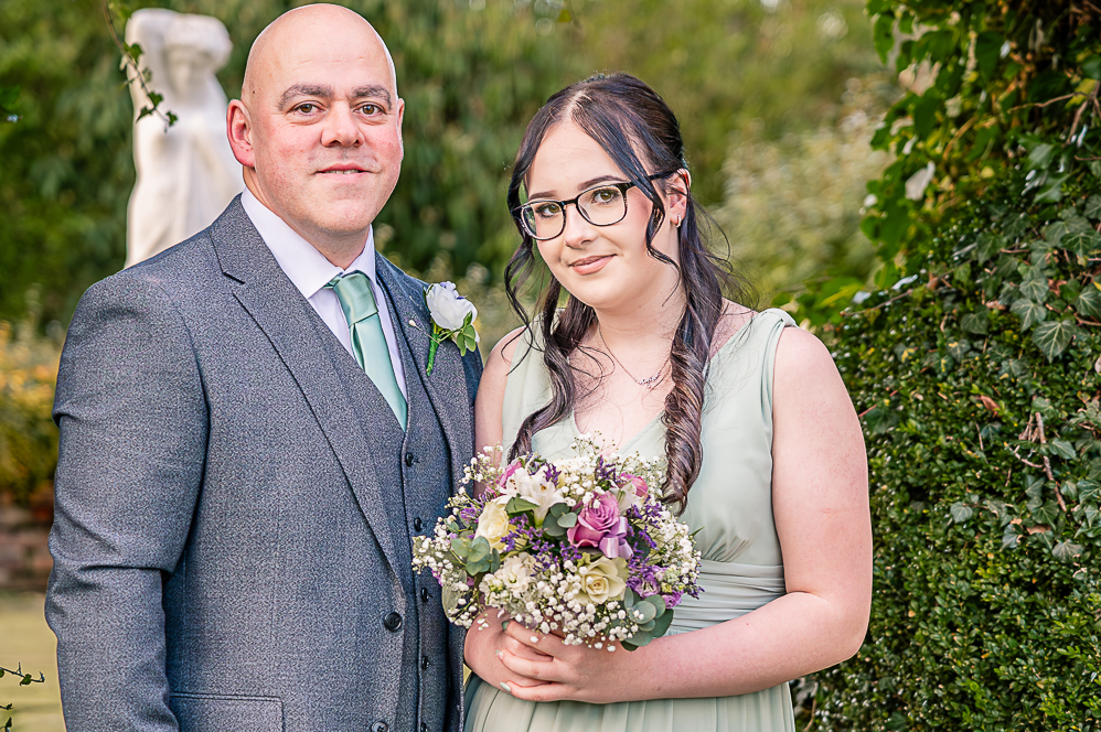 Groom and bridesmaid (girl) under a leaf shaped arch taken by Manchester Photographer Wedding Rebekah Morecroft