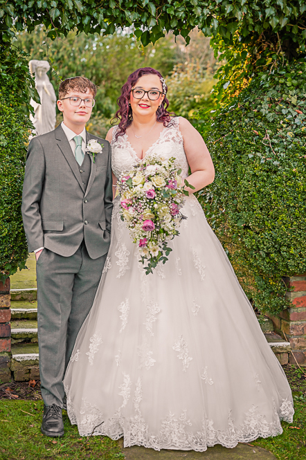Bride and Groomsman (boy) under a leaf shaped arch taken by Manchester Photographer Wedding Rebekah Morecroft