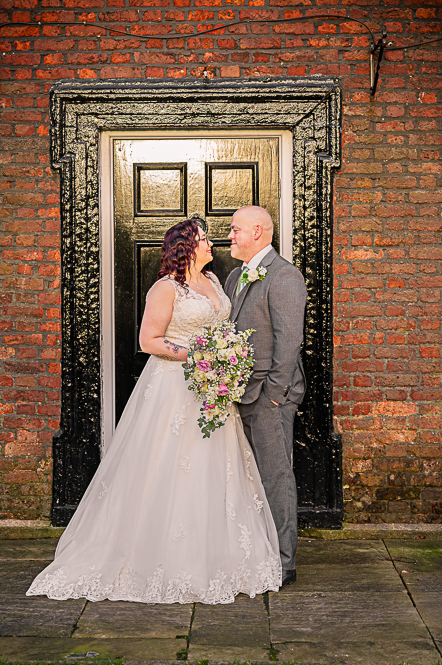 Bride and groom looking at each other in front of Georgian style black door.