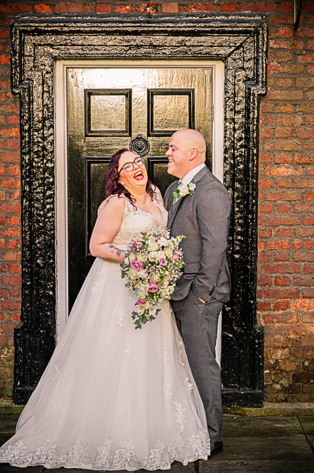 Bride and groom laughing in front of Georgian style black door.
