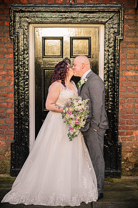 Bride and groom kissing in front of Georgian style black door.
