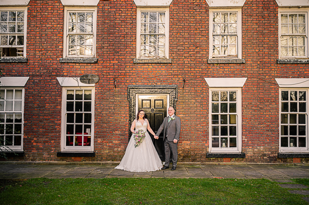 Bride and groom holding hands standing in front of Georgian style building