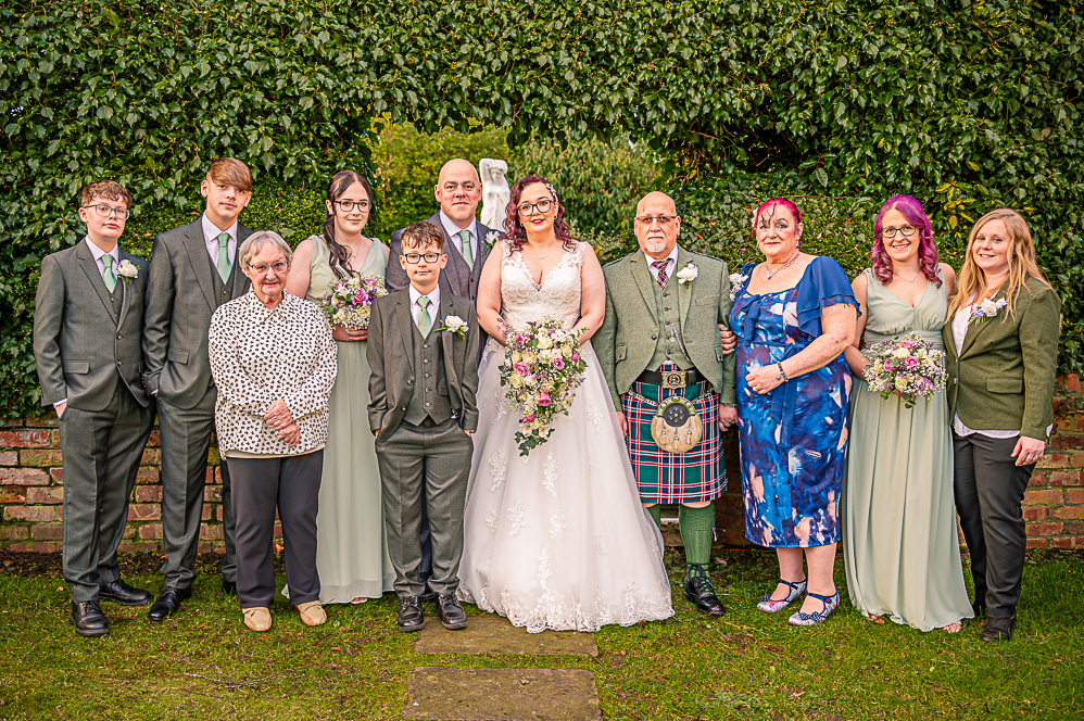 Bride and Groom with brides family with a leaf shaped arch behind them taken by Manchester Photographer Wedding Rebekah Morecroft
