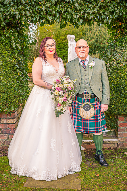 Bride and father of the bride with a leaf shaped arch behind them taken by Manchester Photographer Wedding Rebekah Morecroft