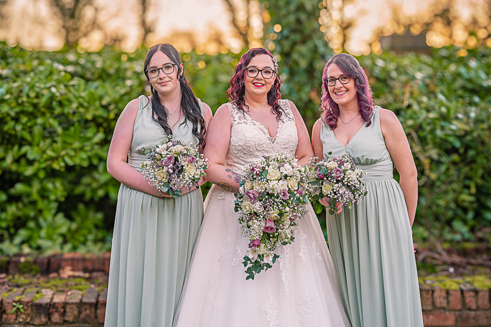 Bride and two bridesmaids with their flowers with sunset behind them taken by Manchester Photographer Wedding Rebekah Morecroft