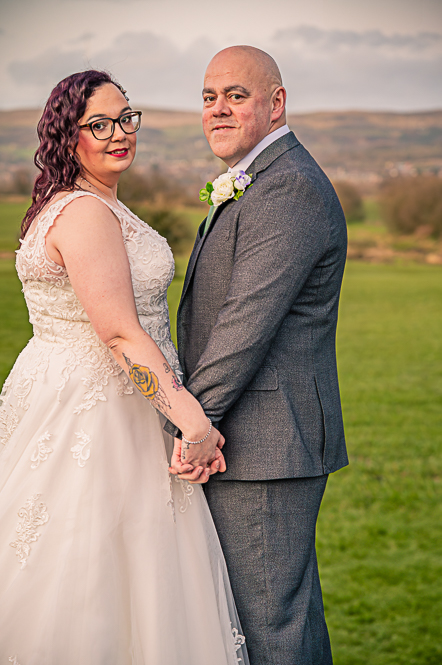 Bride and Groom holding hands with hills behind them.
