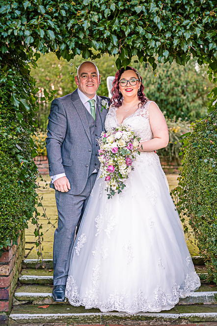 Bride and Groom under a leaf shaped arch taken by Manchester Photographer Wedding Rebekah Morecroft