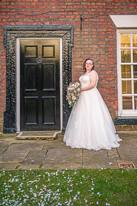 Bride with bouquet standing next to a black door.