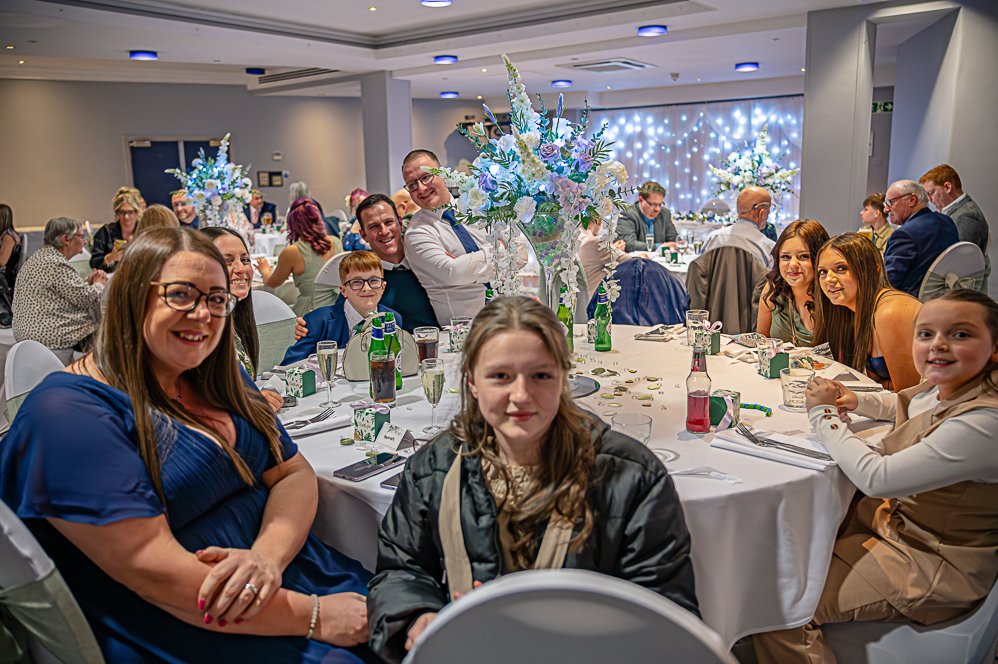Group of wedding guests at table posing for photo