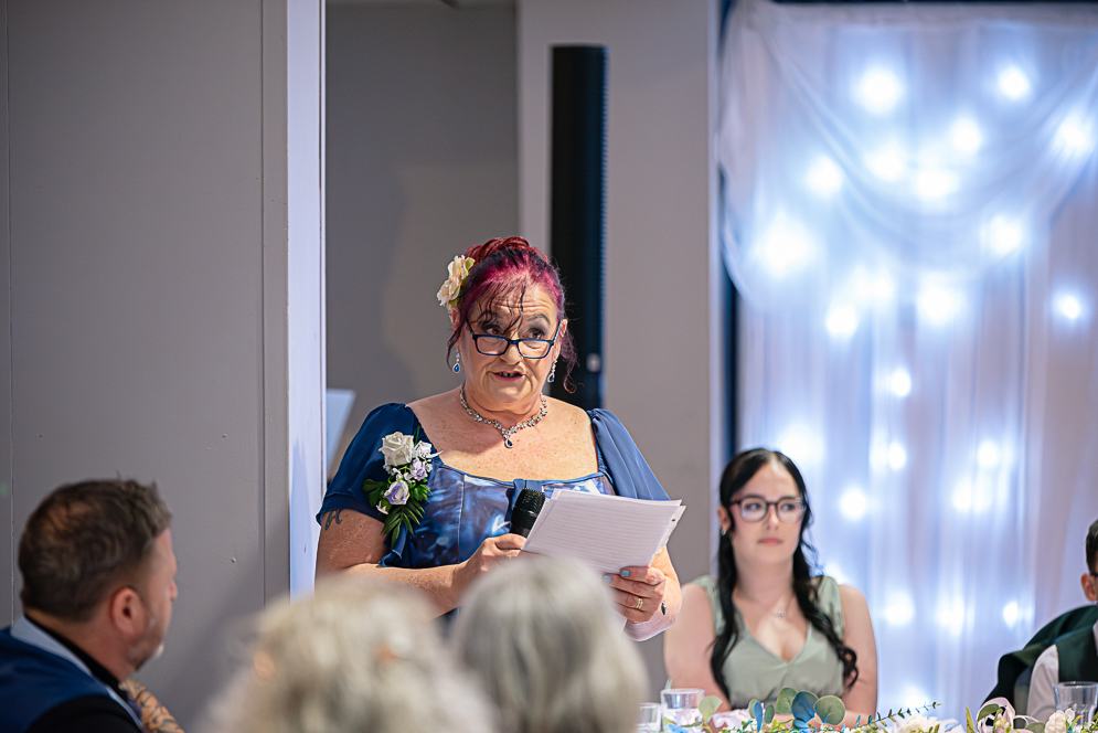 View of wedding guests listening to mother of the bride giving a speech