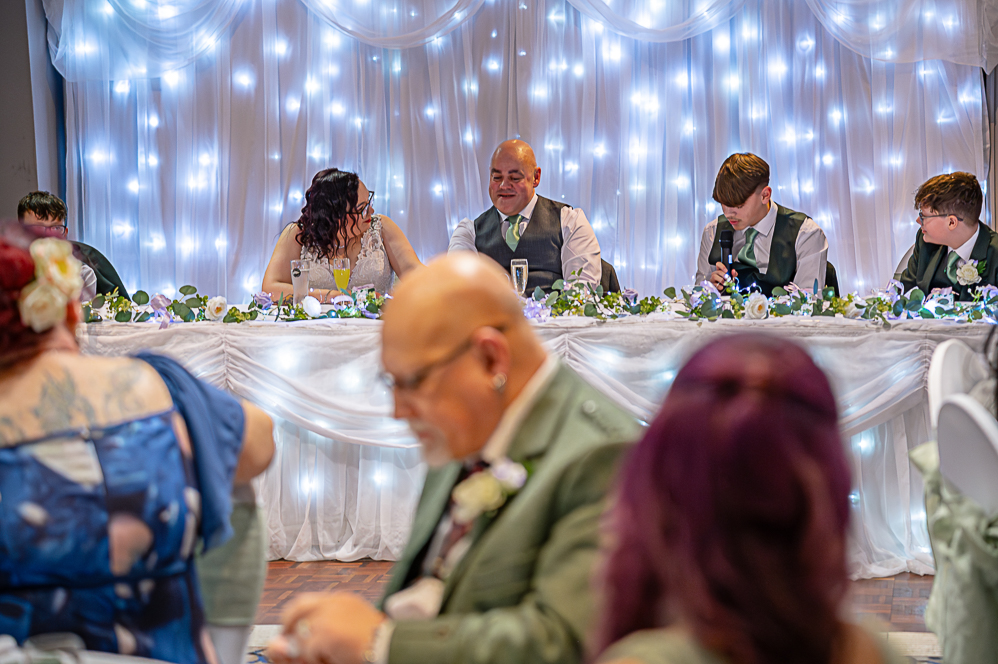 View of wedding guests listening to groomsman giving a speech
