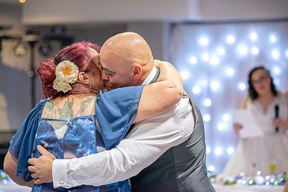 Groom hugging and giving a kiss on the check to Mother of the Bride.