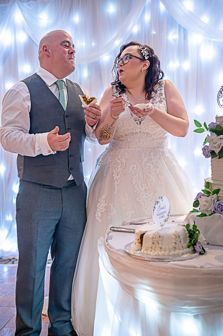 Bride and Groom eating wedding cake next to wedding cake