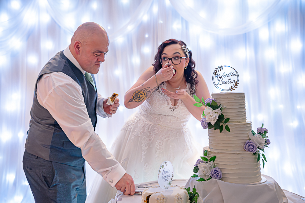 Bride and Groom eating wedding cake next to wedding cake