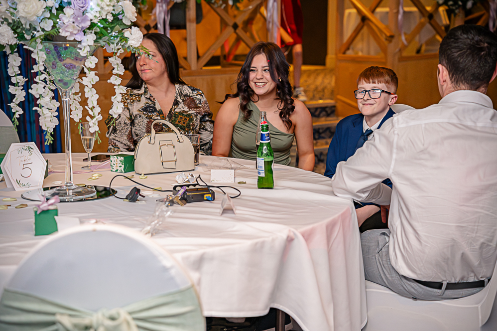 Group of wedding guests at table smiling for photo