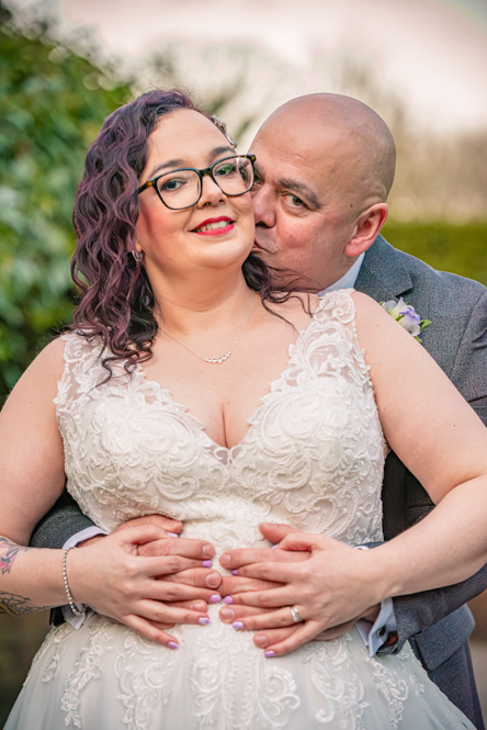 Groom kissing the bride's neck tenderly during couple portraits at a Bolton wedding