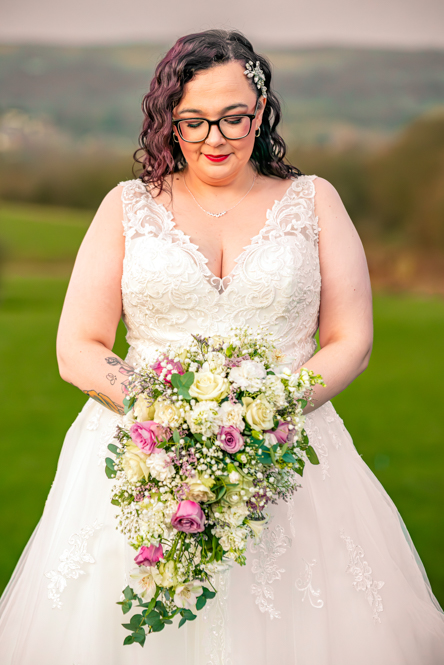 Bride looking down at her Bouquet with hills behind