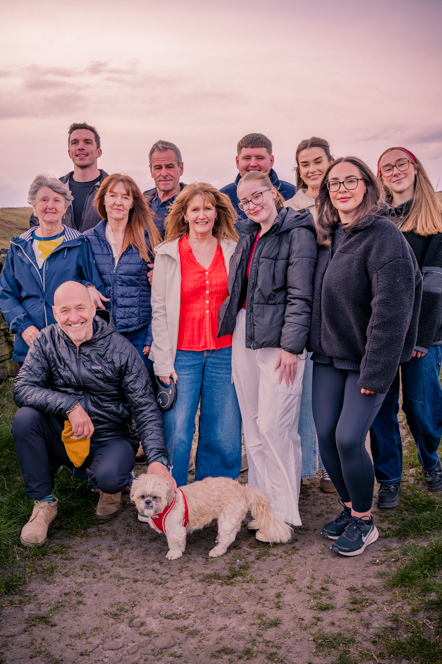 An outside picture of large family of 11 people with dog