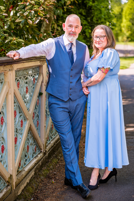 Couple standing together while man's arm is resting on the side of a bridge