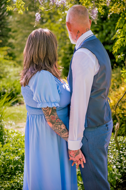 View of the back of the couple holding hands as they look into the garden