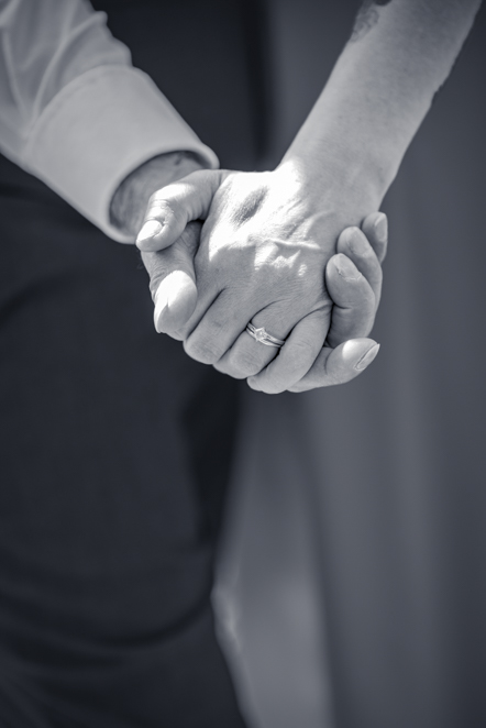 Black-and-white image of Close-up of couple holding hands showing off the ladies engagement ring