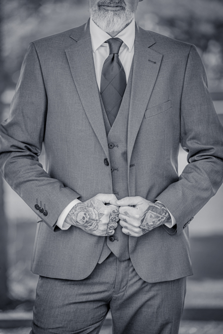Black-and-white image of Close-up of Man holding the front of his suit jacket taken by Manchester Photographer Wedding Rebekah Morecroft