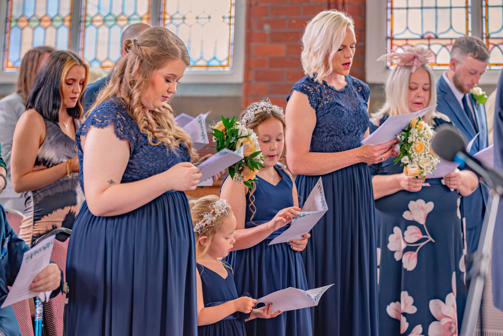 Wedding party and wedding guest singing a hymn