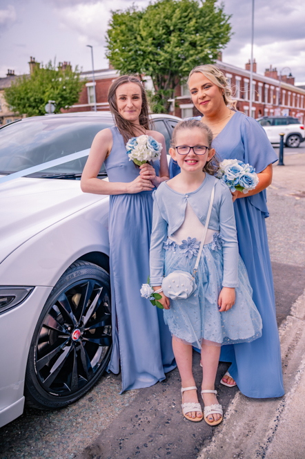 Bridesmaids and flower girl standing next to White Jaguar
