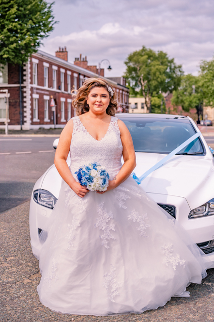 The bride standing in front of a white Jaguar