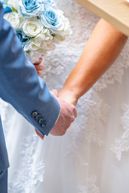 A close-up of the bride and groom holding hands