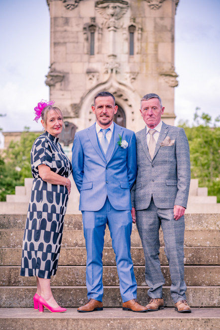 Groom and his parents standing on some steps