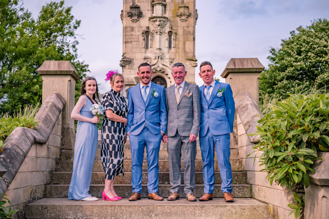 groom with the the grooms parents and siblings standing on some steps