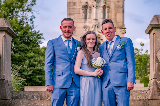 Groom, best man and bridesmaid standing on some steps