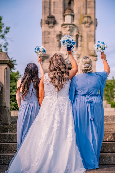 The backs of the bride and her two bridesmaids with their bouquets in the air taken by Manchester Photographer Wedding Rebekah Morecroft who offers wedding photography packages