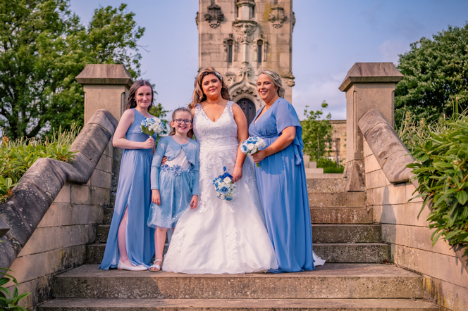 The bride with her two bridesmaids and her flower girl standing on some steps