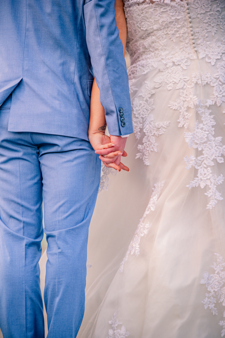 Bride and groom holding hands with their backs to the camera at The Whitehead Clock Tower in Bury
